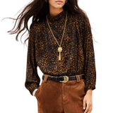 A woman modeling a long-sleeve brown and black patterned top, brown corduroy pants, a black belt, and black ankle boots against a plain white background.