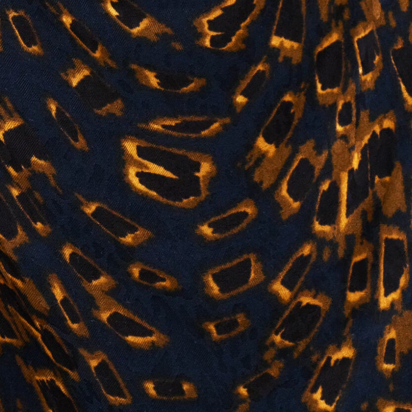 A close-up of a leopard print fabric featuring a dark navy blue base with golden-brown and black irregular spots.